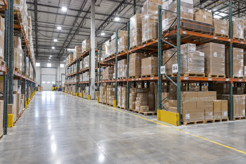 Warehouse aisle illuminated by overhead high-bay fixtures